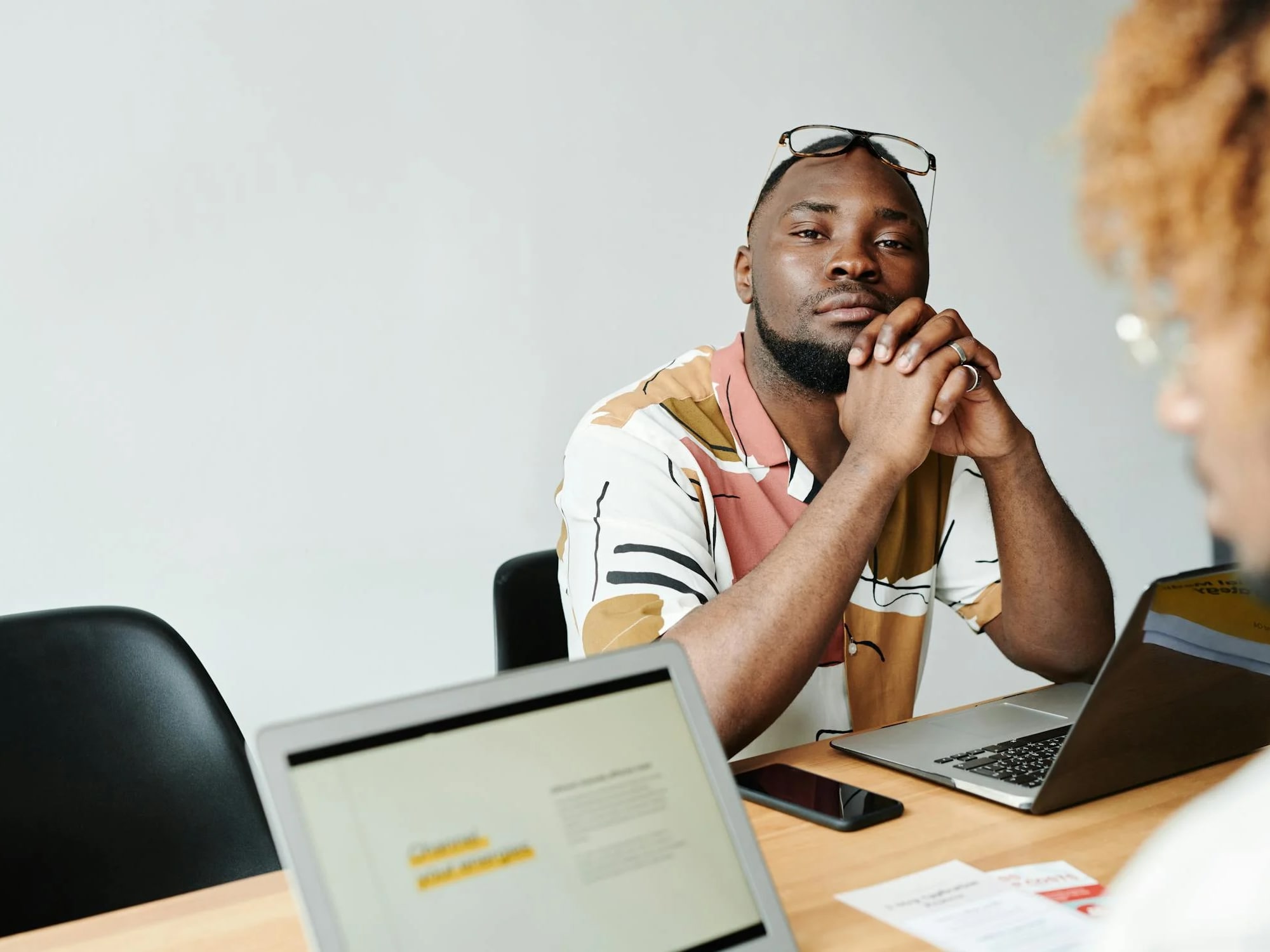 Professional sitting at desk with laptop, looking contemplative during meeting