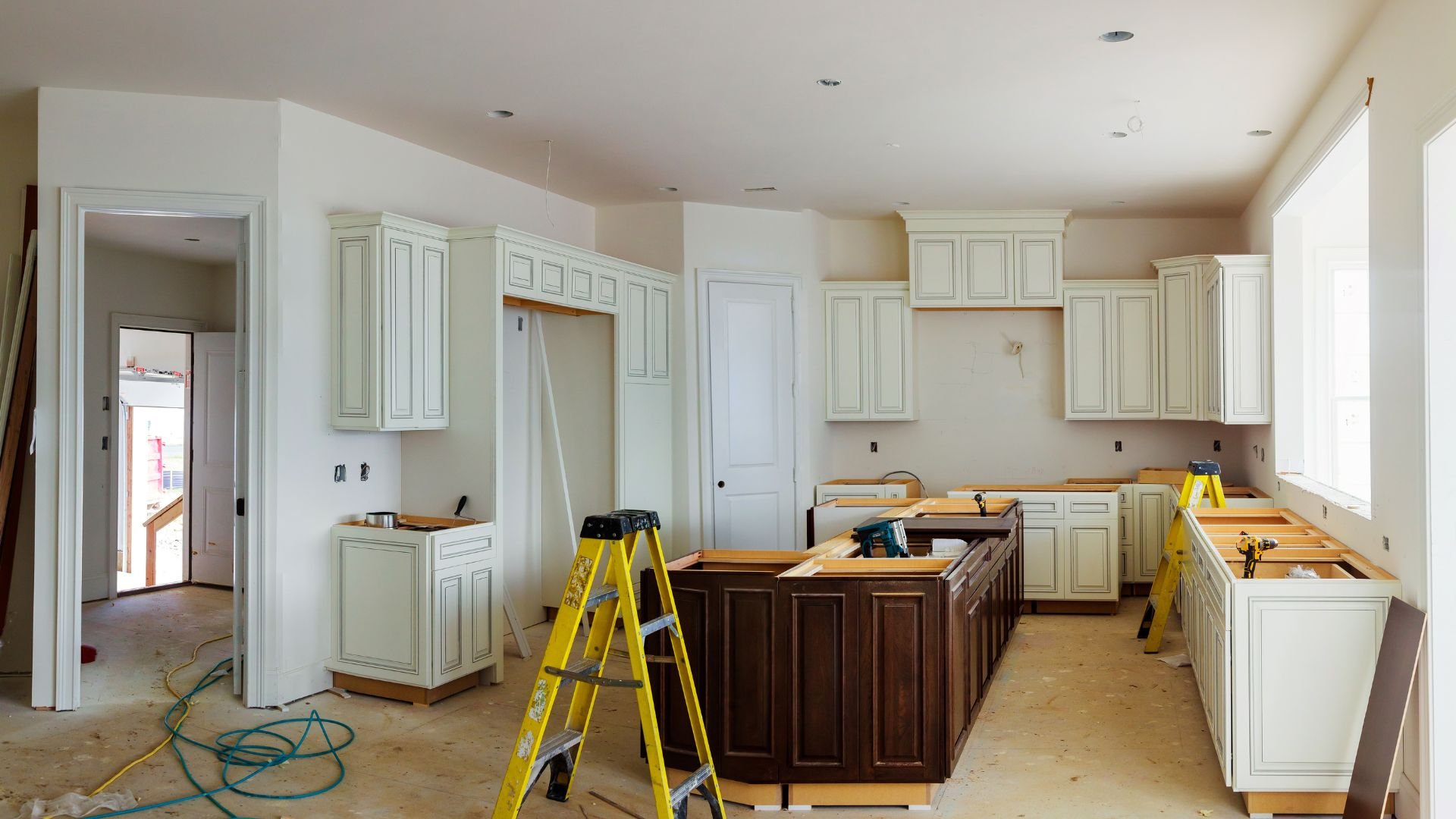 Kitchen renovation in progress with white cabinets and yellow ladders