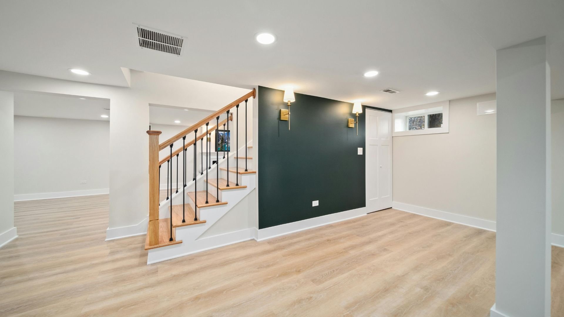 Bright basement interior with wooden stairs and dark accent wall