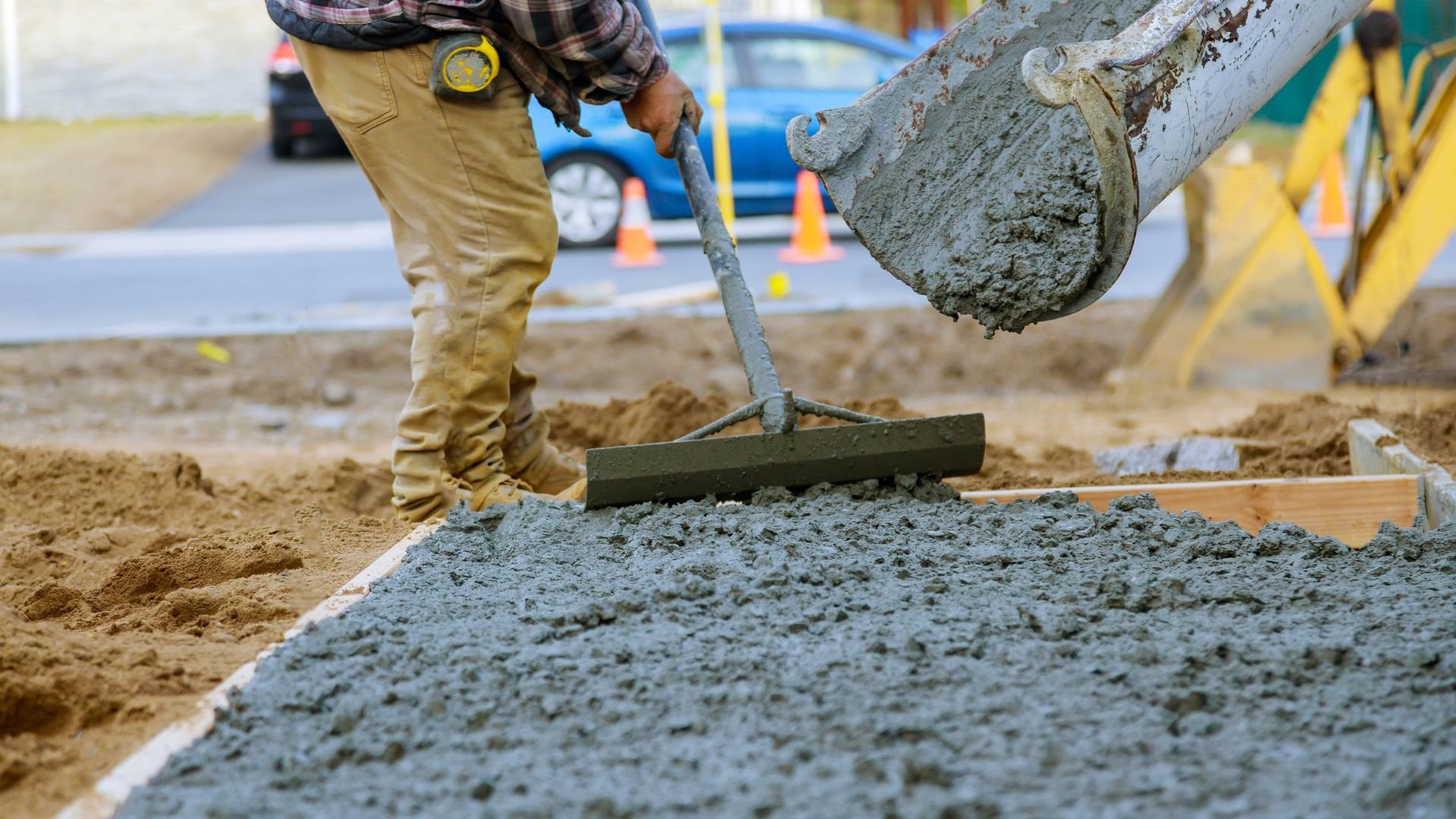 Construction worker smoothing wet concrete with trowel at job site
