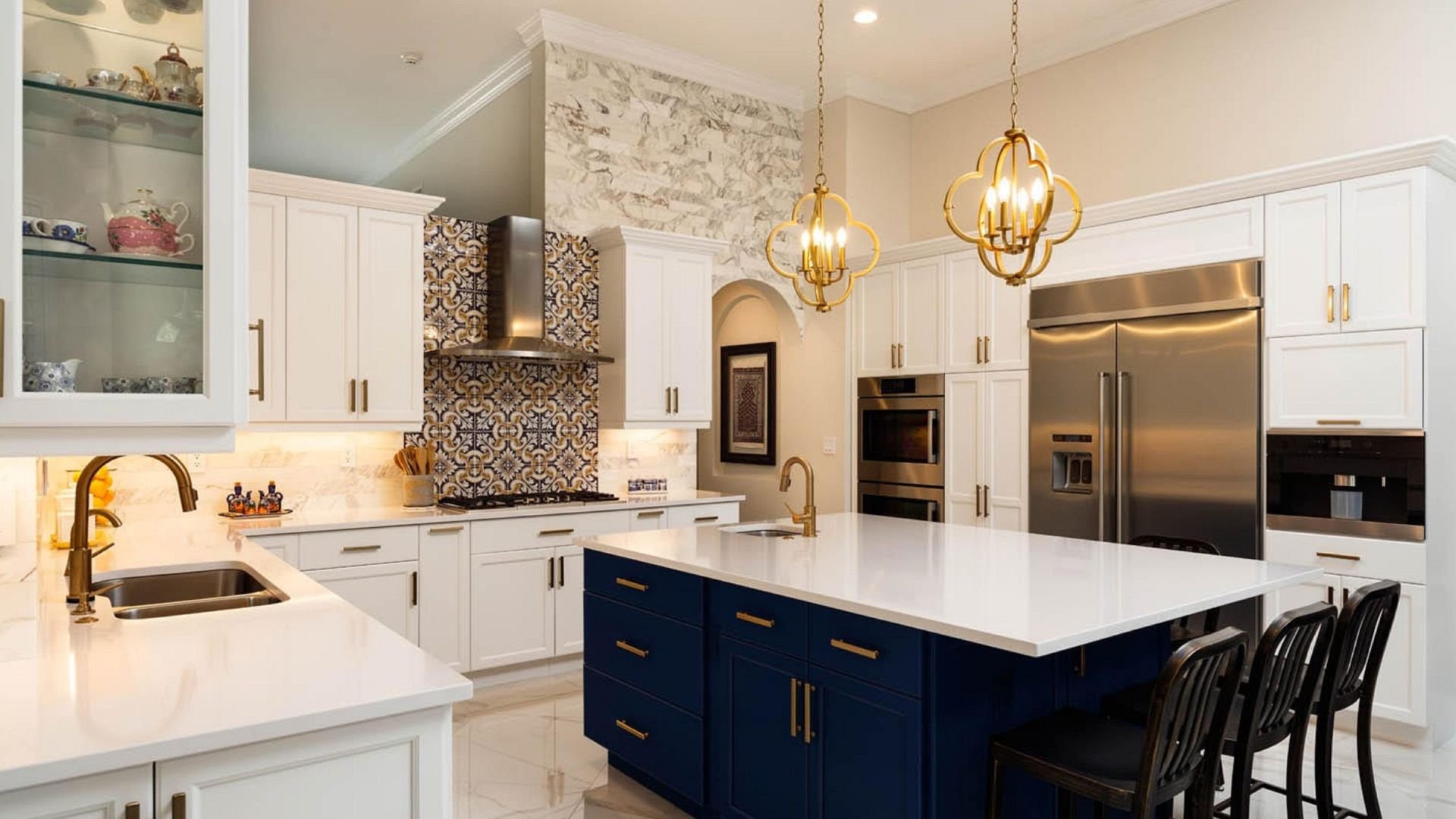 Elegant kitchen with white cabinets, blue island, and gold light fixtures