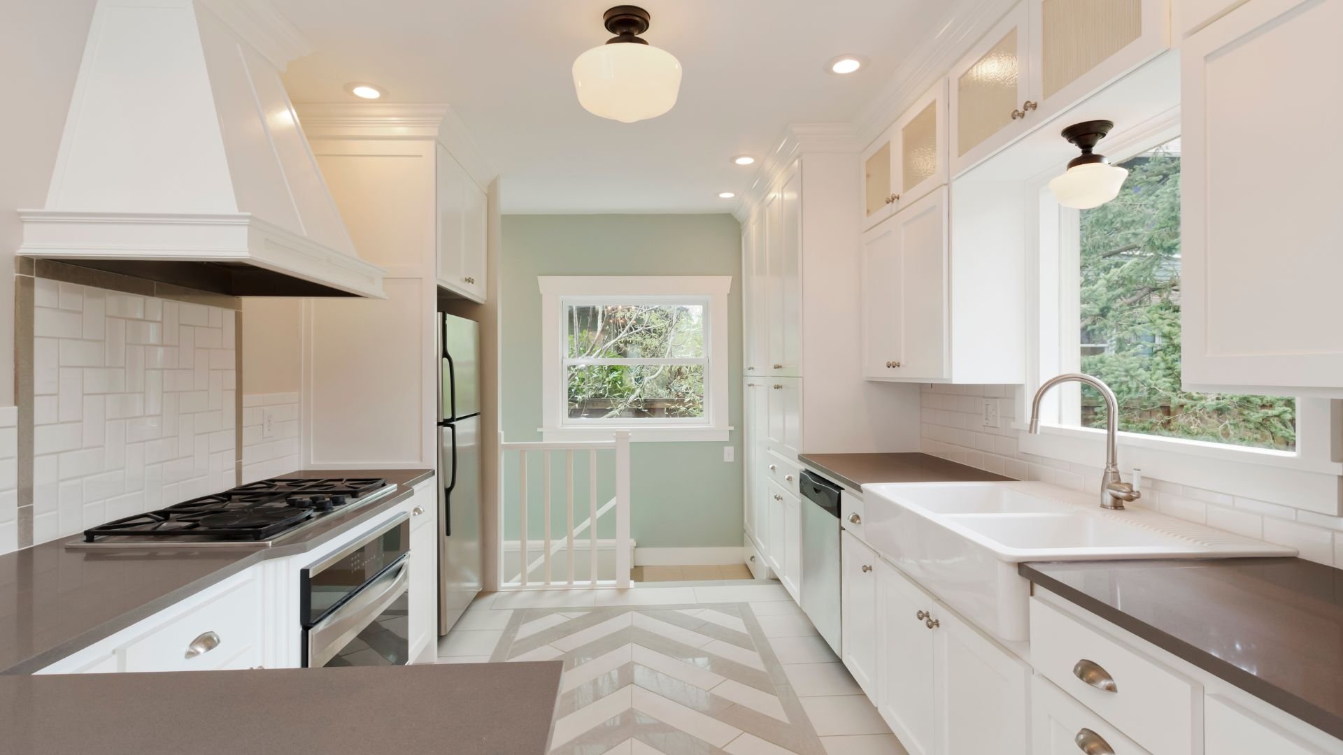 Modern white kitchen with gray countertops and chevron floor pattern