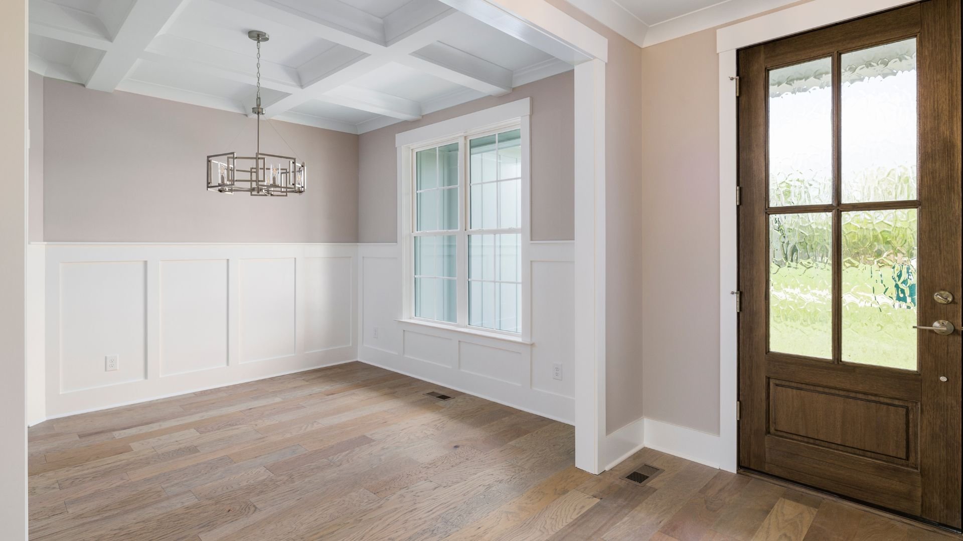 Empty room with wooden floor, white paneling, and glass door